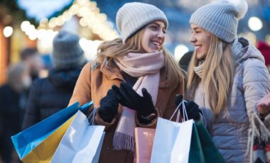 deux femme vetues de vetemets d'hiver, tenant des sacs de shopping, le visage souriant pour évoquer les soldes d'hiver