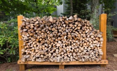 L'image montre un stock de bûches de bois de chauffage soigneusement empilé à l'extérieur, prêt pour une utilisation hivernale.