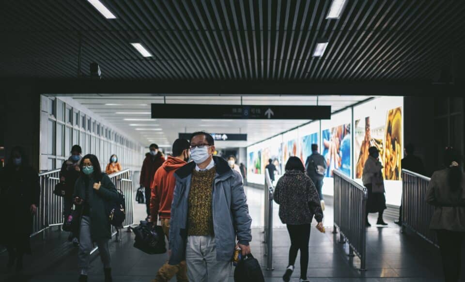 L'image montre des personnes portant des masques dans un espace public en Chine, illustrant les préoccupations liées à la circulation des virus respiratoires.