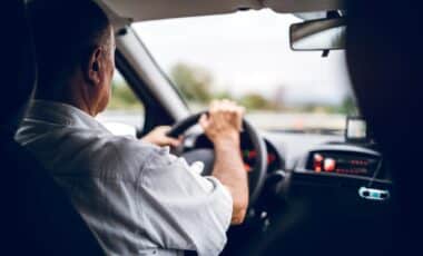 Un conducteur âgé est au volant d'une voiture, concentré sur la route. L'image illustre la thématique de l'âge de conduire des seniors, soulignant la question de leur capacité à rester au volant en toute sécurité malgré l'âge.