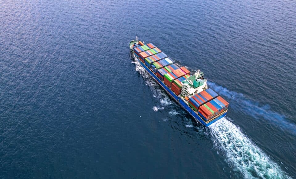 Un cargo transportant des conteneurs en mer, symbolisant le commerce international et le déficit commercial.