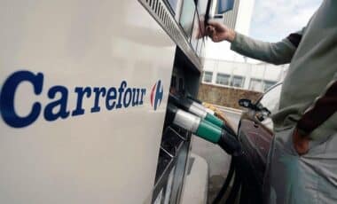 L'image montre une station-service Carrefour avec des pistolets de distribution de carburant, évoquant une offre ou un service lié au carburant proposé par l'enseigne.