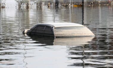 Une voiture est partiellement submergée par une inondation, illustrant les risques climatiques et la nécessité d'une assurance auto couvrant les catastrophes naturelles.