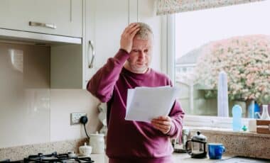 Un homme semble préoccupé en consultant sa facture, illustrant l'impact des hausses de tarifs de l'électricité sur les ménages.