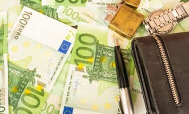 Des billets de 100 euros, un portefeuille et une montre, illustrant le sujet des salaires des fonctionnaires et les préoccupations liées à leur paiement.