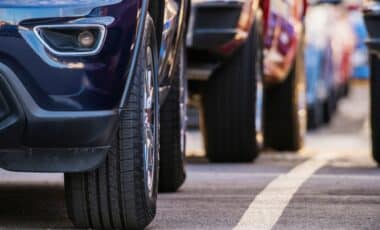 L'image montre une rangée de voitures stationnées, mettant en évidence leurs roues et la partie avant, suggérant un contexte lié au marché automobile ou à un stationnement.