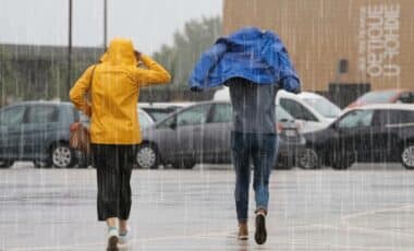 deux personnes marchant sous une météo pluvieuse et venteuse