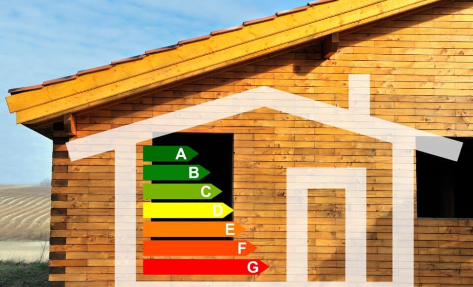 L'image représente une maison en bois avec un graphique de performance énergétique, de A (vert) à G (rouge), symbolisant les passoires thermiques et l'évaluation énergétique des logements. pour évoquer les passoires thermiques.