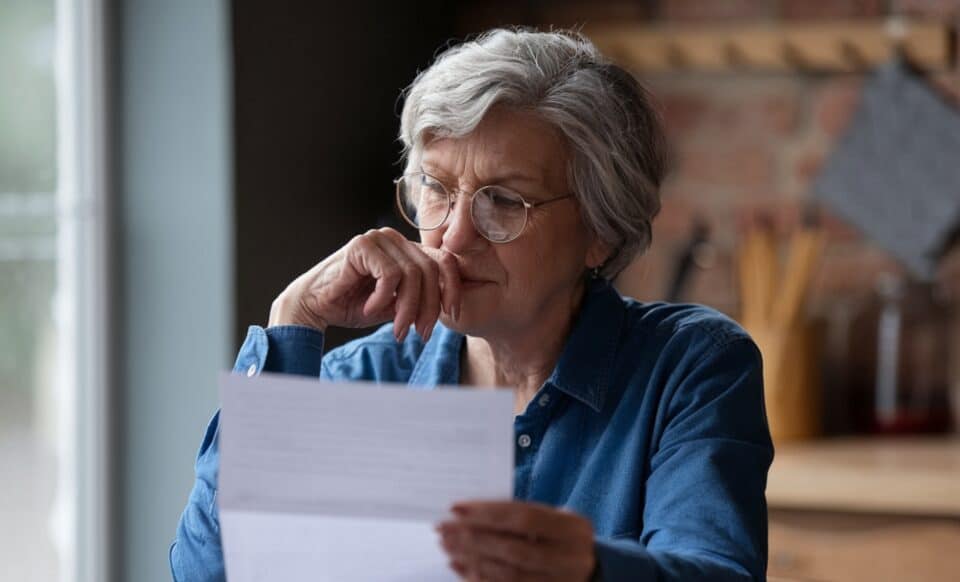 Une personne âgée consultant un document pour évoquer la hausse de la pension de réversion