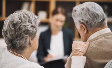 Un couple senior consulte une conseillère, illustrant une discussion liée à la pension de réversion et ses démarches administratives.