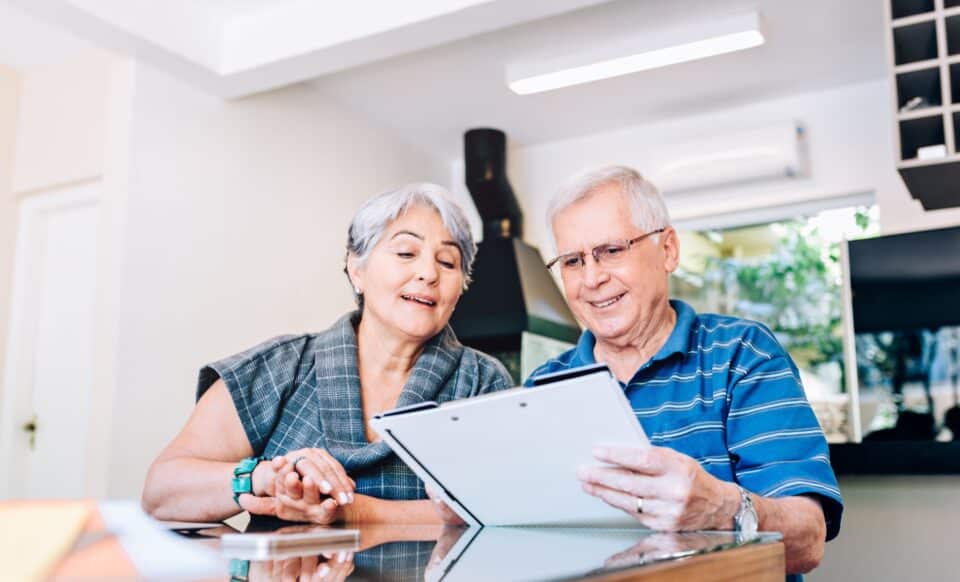 Un couple de seniors examine un document à domicile, illustrant une réflexion ou une planification liée à la réforme des retraites.