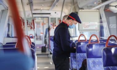 Cette image montre un contrôleur en uniforme dans un train, symbolisant les opérations de vérification dans les transports publics, notamment à la SNCF et à la RATP.