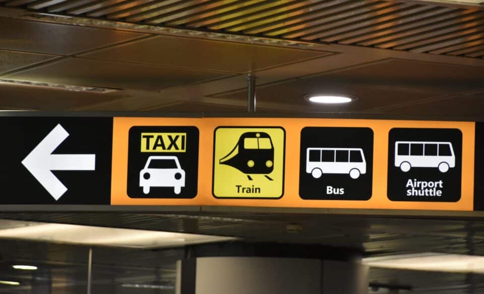 L'image montre un panneau d'orientation dans une gare ou un aéroport indiquant les différents modes de transport disponibles en Île-de-France : taxi, train, bus et navette aéroport.