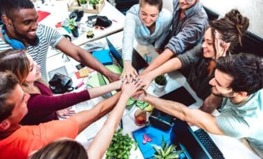 Cette image montre un groupe de personnes collaborant autour d'une table, symbolisant l'entraide et la solidarité. Elle pourrait illustrer le travail collectif et les discussions autour des droits et de la régularisation des travailleurs sans-papiers dans les secteurs des métiers en tension.