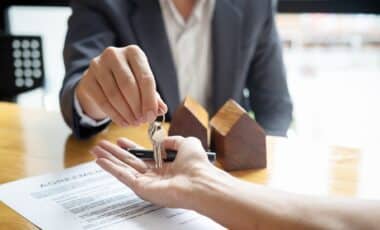 Remise de clés lors d'une signature de contrat immobilier, illustrant une transaction soumise aux frais de notaire.