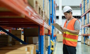 Un professionnel en entrepôt effectue un contrôle de stocks, illustrant un métier clé dans la gestion logistique.