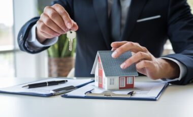 Une personne tenant dans une main des clés d'un logement et une maison en miniature avec l'autre main pour illustrer le crédit immobilier