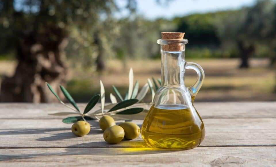 Une bouteille d'huile d'olive devant des olives de table pour illustrer le rappel produit de l'huile Monoprix