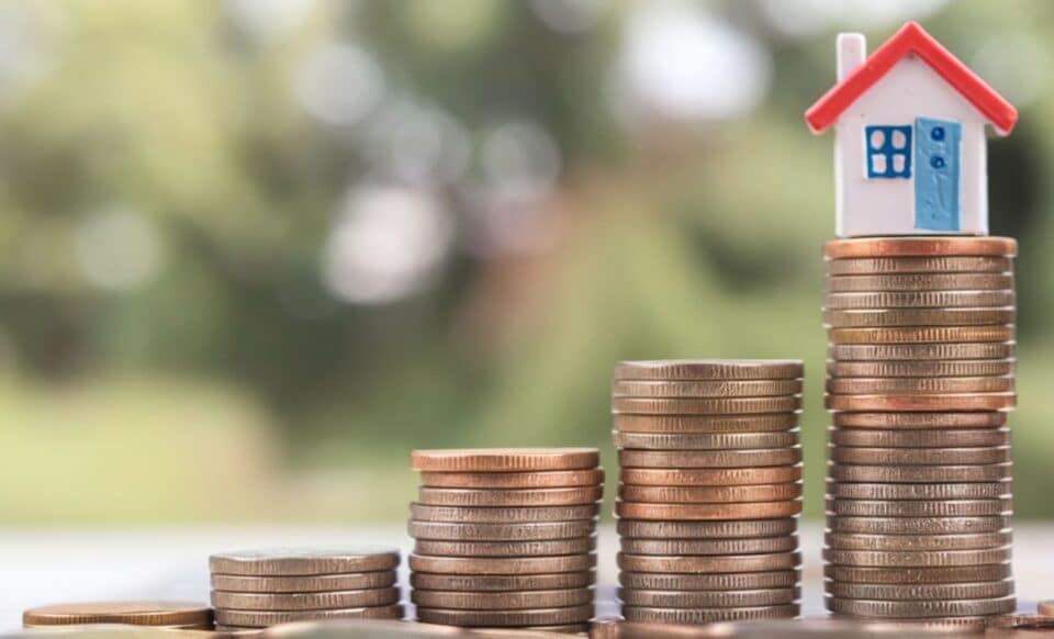 Une maison miniature sur un tas de pièces de monnaie pour évoquer les SCPI