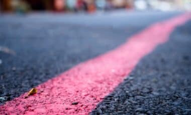 Gros plan sur une ligne rouge tracée sur la chaussée, un nouveau marquage routier destiné à renforcer la sécurité.