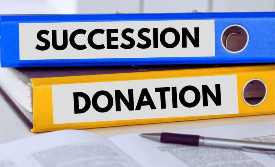 Deux classeurs étiquetés "Succession" et "Donation" posés sur un bureau, illustrant la gestion du patrimoine et des héritages.