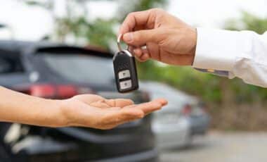 Une clé de voiture est remise d’une main à une autre, symbolisant la vente ou l’échange d’un véhicule.